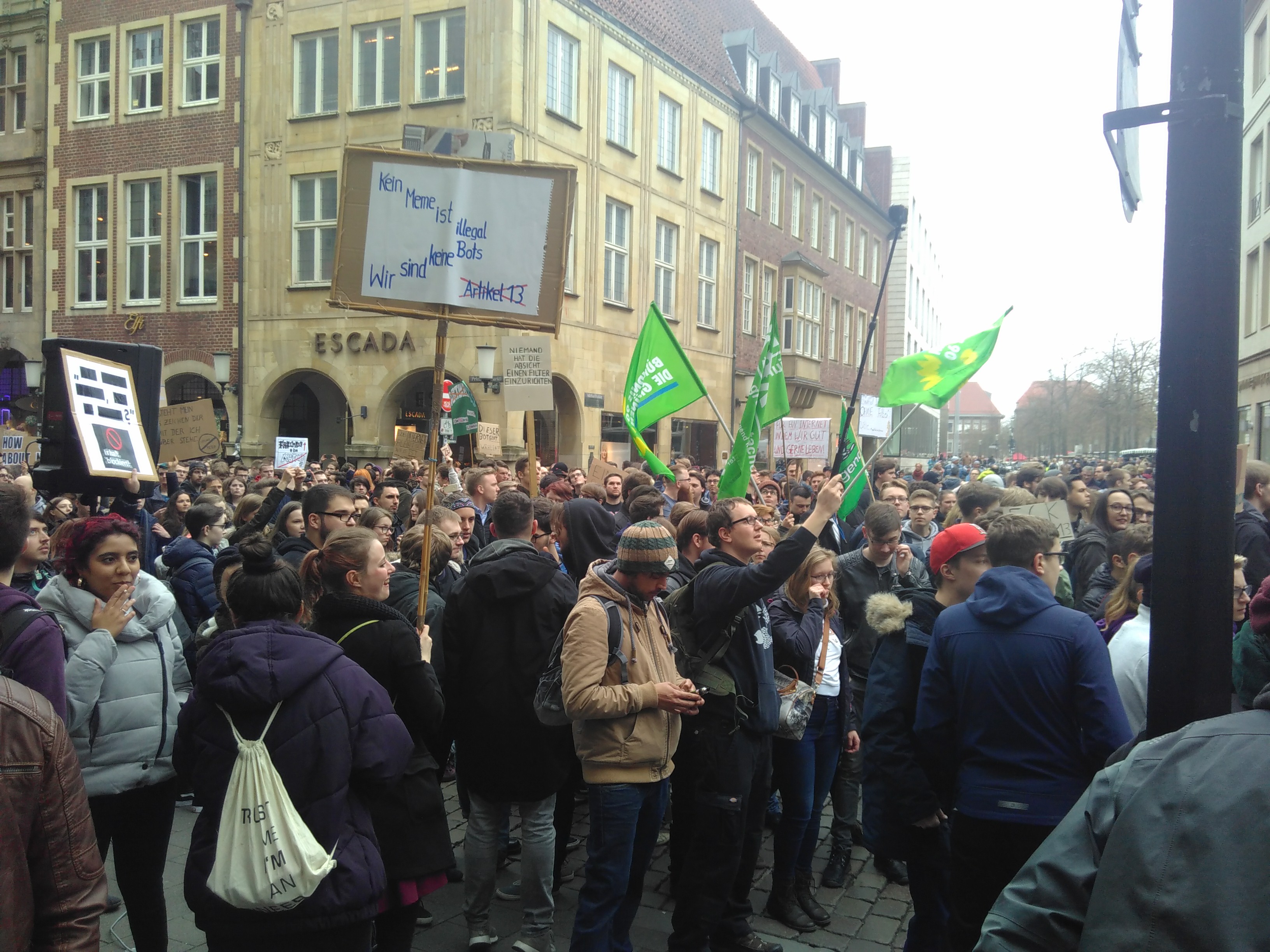 Viele Menschen stehen auf dem Prinzipalmarkt. Einige Menschen halten Fahnen der Grünen. Andere Menschen halten Plakate.