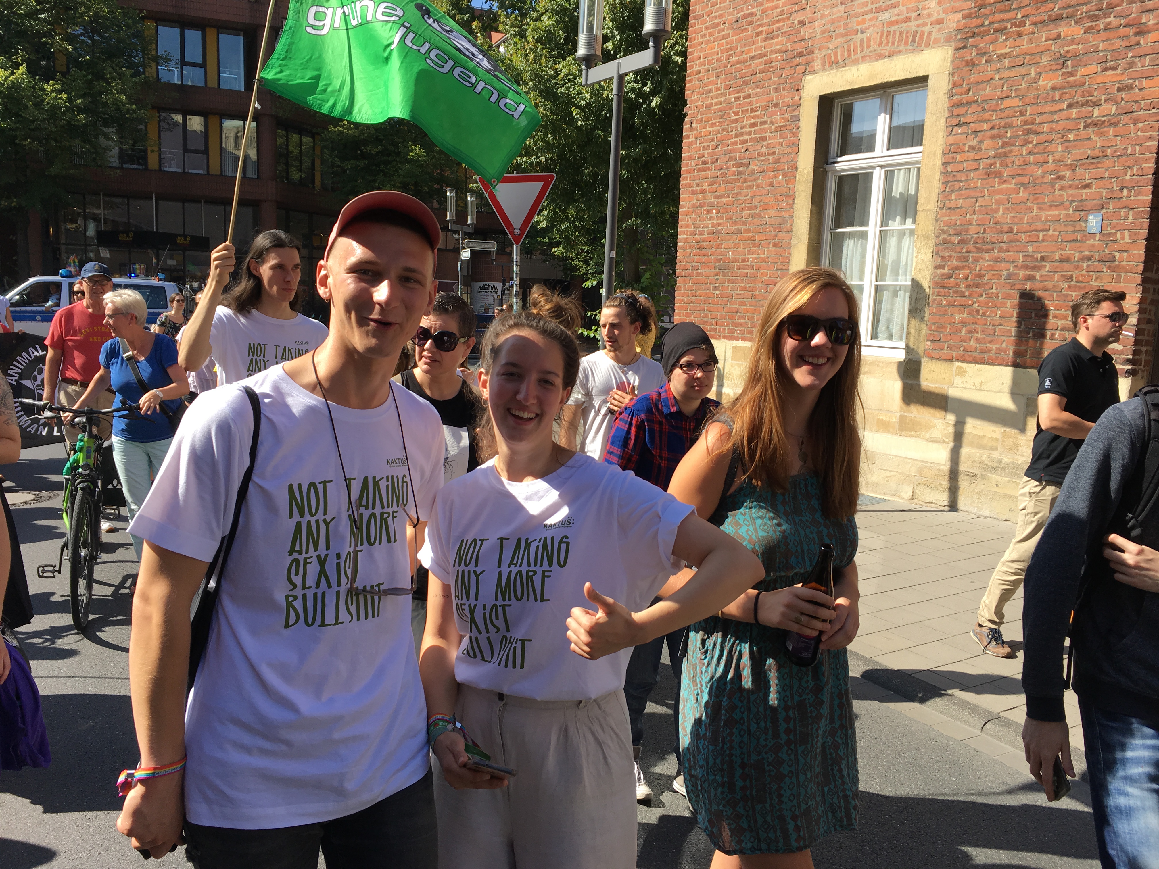 Viele Menschen auf einer Straße. Ein Mensch hält eine Fahne der Grünen Jugend.