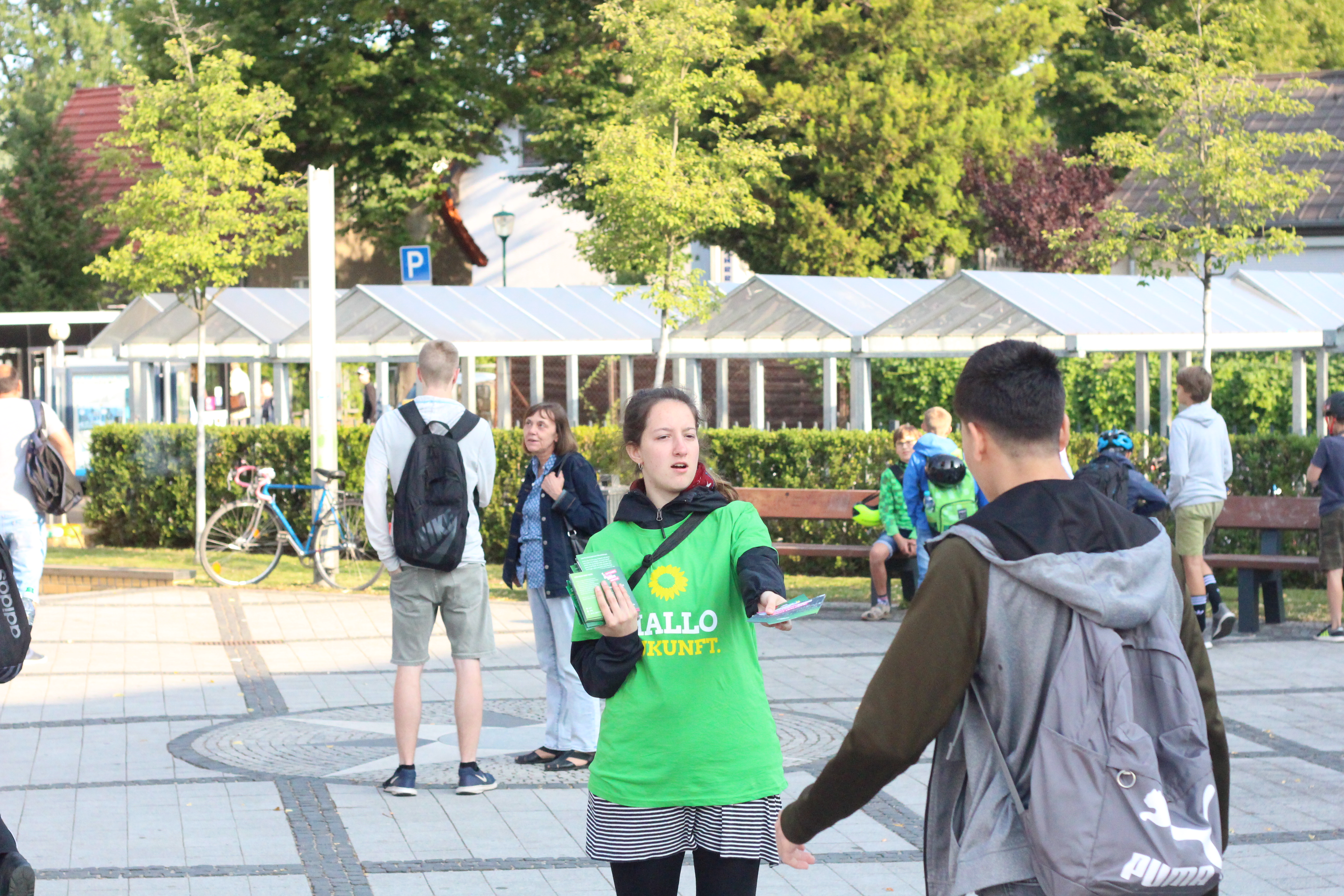 Eine Person mit einem T-Shirt der Grünen verteilt Informationen